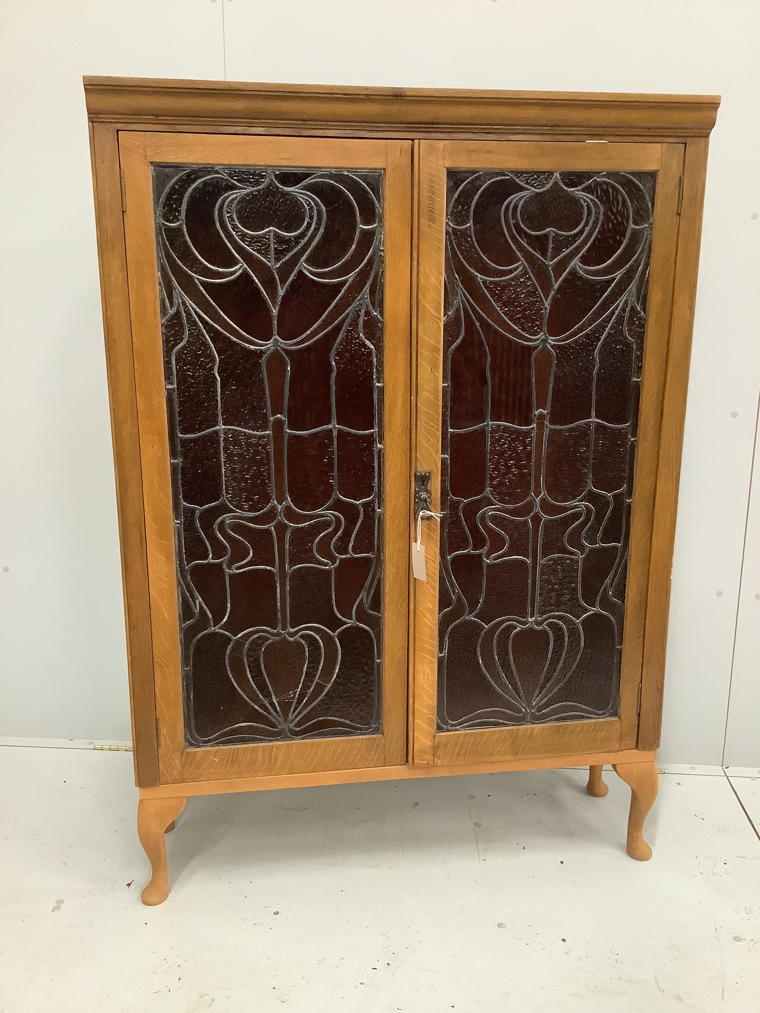 A pair of Art Nouveau stained glass panels, now as an oak bookcase, width 104cm, depth 29cm, height 150cm